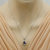 Silver necklace with a pendant on a mannequin wearing a beige dress.
